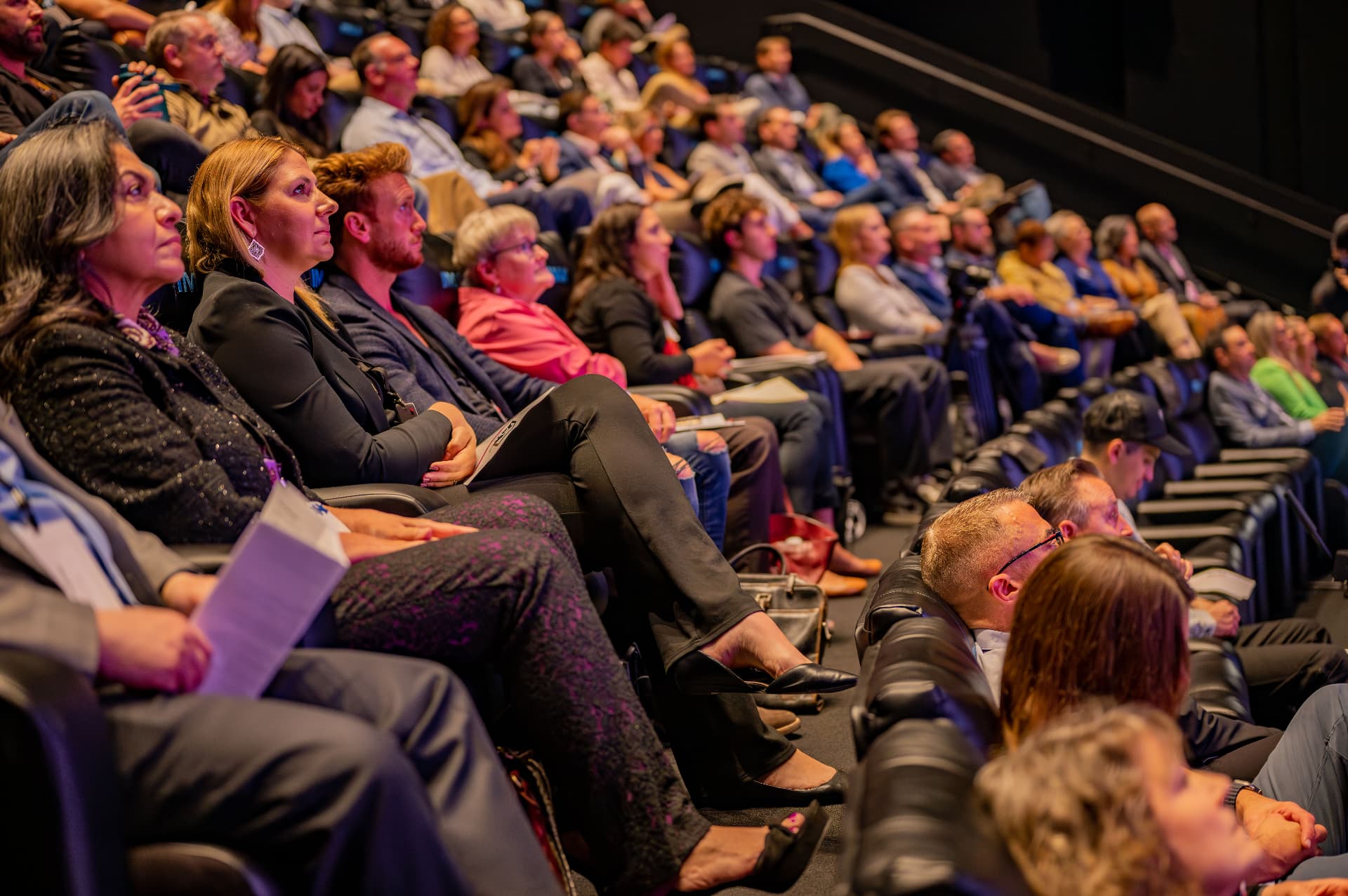 Rows of executives seated in a theater watching a keynote