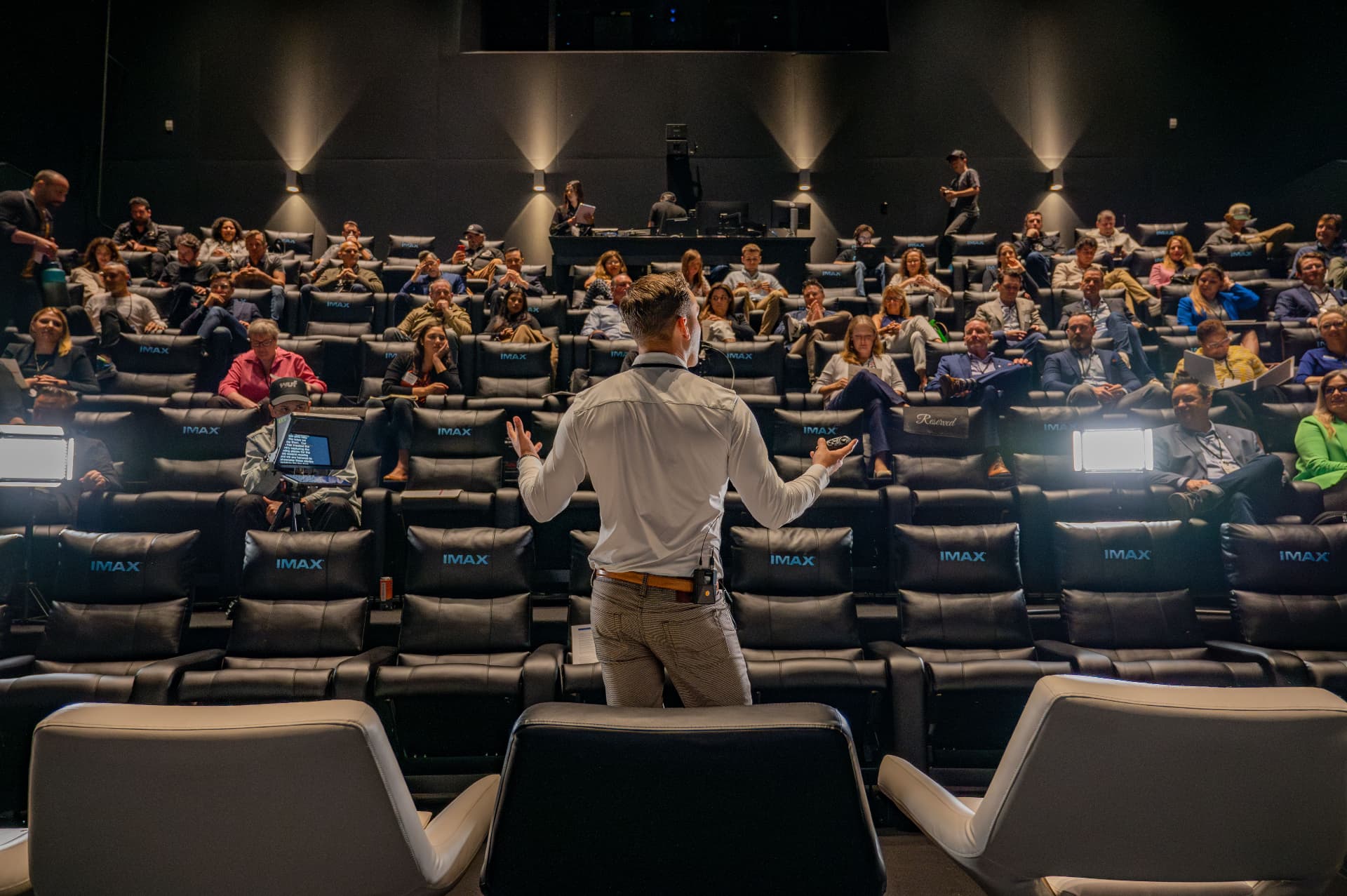 Speaker addressing a packed IMAX theater of executives